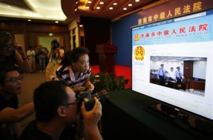 A journalist takes pictures of a screen displaying a court's microblog page showing disgraced Chinese politician Bo Xilai standing trial inside the court in Jinan, Shandong province, on August 22, 2013. (REUTERS/Carlos Barria)