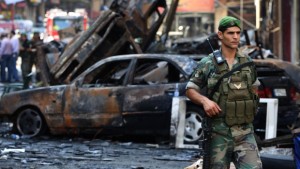 In this Friday August 16, 2013, file photo, a Lebanese army soldier passes in front of burned cars at the site of a car bomb explosion in an overwhelmingly Shiite area and stronghold of the Lebanese militant group Hezbollah, in the southern suburbs of Beirut, Lebanon. (AP Photo/Hussein Malla, File)