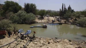 On May 26, 2013, a group of men smuggle diesel fuel from Syria to Turkey cross the Al-Assi River in Darkush town, Idlib countryside, hoping to sell it at a higher price. (REUTERS/Muzaffar Salman)