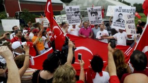 Armagan Yilmaz, center, holds his infant daughter as he speaks to the crowd of approximately 130 people assembled in Saylorsburg, Pa. on Saturday, July 13, 2013 to demonstrate against Turkish cleric Fethullah Gülen, who lives in town. (AP Photo/Pocono Record, Keith R. Stevenson)
