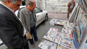 Iranians look at newspapers displayed on the ground outside a kiosk in Tehran on November 25, 2013. (AFP PHOTO/ATTA KENARE)