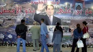 People stand in front of a poster in Tunis showing President Zine El-Abidine Ben Ali on the eve of the 16th anniversary of his accession to power, November 6, 2003. (Fethi Belaid/AFP/Getty Images)
