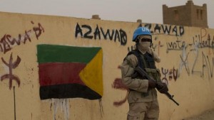 In this Sunday, July, 28, 2013 file photo, a United Nations peacekeeper stands guard at the entrance to a polling station covered in separatist flags and graffiti supporting the creation of the independent state of Azawad, in Kidal, Mali (AP Photo/Rebecca Blackwell, File)