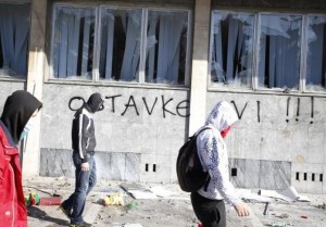 Protesters walk in front of a damaged government building in Tuzla February 7, 2014. REUTERS/Dado Ruvic (Bosnia and Herzegovina - Tags: politics, civil, unrest)