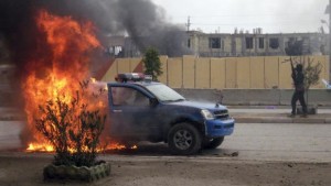In this Wednesday, January 1, 2014, file photo, an insurgent stands guard after setting fire to an Iraqi police truck in front of the provincial government headquarters in Fallujah, Iraq. (AP Photo, File)