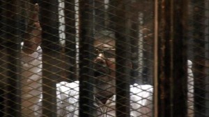 Ousted Egyptian President Mohammed Morsi talks from a cage in a makeshift courtroom inside a police academy in Cairo, Egypt, 28 January 2014.