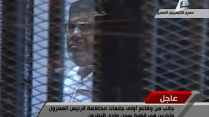 Deposed Egyptian President Mohamed Mursi of the Muslim Brotherhood stands inside his glass cage during his trial at a Cairo police academy January 28, 2014. Mursi went on trial on charges in connection with a mass jail break during the 2011 uprising, state television reported. REUTERS/Egyptian State TV via Reuters TV (EGYPT - Tags: POLITICS CRIME LAW) NO SALES. NO ARCHIVES. FOR EDITORIAL USE ONLY. NOT FOR SALE FOR MARKETING OR ADVERTISING CAMPAIGNS. EGYPT OUT. NO COMMERCIAL OR EDITORIAL SALES IN EGYPT