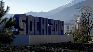 The Caucasus Mountains rise beyond a sign for the Sochi Olympics Thursday, Feb. 6, 2014, in Rosa Khutor, Russia. The area will host the alpine events at the 2014 Winter Olympics which opens Friday, Feb. 7. (AP Photo/Charlie Riedel)