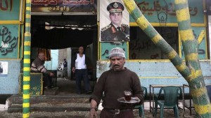 A waiter serves tea in a public cafe where a poster for Egypt's army chief, Field Marshal Abdel-Fattah El-Sisi, is hung on a wall, in Cairo on March 16, 2014. (REUTERS/Asmaa Waguih)
