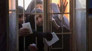Iraqi women wait behind a window to receive their electronic voter ID cards in the capital Baghdad on February 25, 2014, ahead of legislative elections in April. (AFP PHOTO/AHMAD AL-RUBAYE)