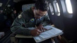 A Royal Malaysian Air Force Navigator captain, Izam Fareq Hassan works on a map onboard a Malaysian Air Force CN235 aircraft during a search and rescue (SAR) operation to find the missing Malaysia Airlines flight MH370 plane over the Strait of Malacca. (AFP PHOTO/MOHD RASFAN)