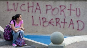 epa04135625 A woman sits in front of a graffitti saying: 'Fight for your freedom' during a demonstration against the Venezuelan government of Nicolás Maduro at Altamira square in Caracas, Venezuela, on March 21, 2014. (EPA/SANTI DONAIRE)