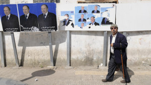 A man walks past electoral posters for incumbent President Abdelazis Bouteflika (L), and candidate Ali Benflis on Tuesday, April 15, 2014, in Algiers. (AP Photo/Ouahab Hebbat)