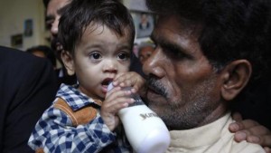 Nine-month-old Musa Khan drinks milk from his bottle while being carried by his grandfather, Muhammad Yasin, as they leave after appearing in a court in Lahore on April 12, 2014. (REUTERS/MOHSIN RAZA)
