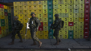 Army soldiers walk beside beer crates during an operation to occupy the Mare slum complex in Rio de Janeiro, Brazil, Saturday, April 5, 2014. More than 2,000 Brazilian Army soldiers moved into the Mare slum complex early Saturday in a bid to improve security and drive out the heavily armed drug gangs that have ruled the sprawling slum for decades. (AP Photo/Silvia Izquierdo)