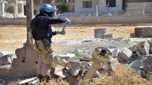This Wednesday, August 28, 2013, citizen journalism file image provided by the United media office of Arbeen which has been authenticated based on its contents and other AP reporting, shows a member of UN investigation team taking samples of sands near a part of a missile that is likely to be one of the chemical rockets according to activists in Damascus countryside of Ain Terma, Syria. (AP Photo/United media office of Arbeen, File)