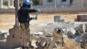 This Wednesday, August 28, 2013, citizen journalism file photo provided by the United media office of Arbeen which has been authenticated based on its contents and other AP reporting, shows a member of a UN investigation team taking samples of sands near a part of a missile that is likely to be one of the chemical rockets according to activists, in Damascus countryside of Ain Terma, Syria. (AP Photo/United media office of Arbeen, File)