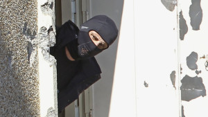 A masked police officer searches for clues at terrorist Mohamed Merah's apartment building in Toulouse, southern France, in this March 23, 2014, file photo. (AP Photo/Remy de la Mauviniere)