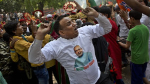 A supporter wears a t-shirt with a portrait of Bharatiya Janata Party (BJP) leader and India’s next prime minister Narendra Modi as he dances with others outside the BJP party in New Delhi, on Friday, May 16, 2014. (AP Photo/Bernat Armangue)