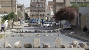 People walk on a street blocked by rocks after clashes between policemen and armed followers of the Houthi movement near the group's political bureau headquarters in Sana'a on June 21, 2014. (REUTERS/Khaled Abdullah)