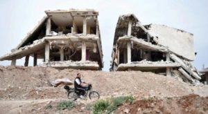 A man in Syriamn village in central Syria passing by a destructed building
