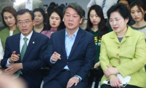 Ahn Cheol-Soo (C), co-chairman of the opposition People's Party of Korea, with party members, watch a television report on an exit poll of the new members of the National Assembly.