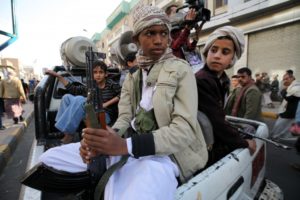 Boys who are part of the Houthi fighters hold weapons as they ride on the back of a patrol truck in Sanaa March 13, 2015, REUTERS