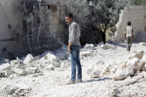 A man inspects the damage at a site hit by an airstrike in the rebel-controlled area of Jarjnaz village in Idlib province
