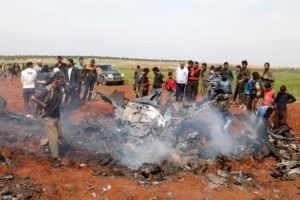 Fighters and civilians gather around the wreckage of a Syrian warplane that was shot down in the Talat al-Iss area, south of Aleppo