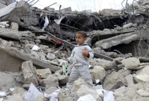 A boy walks as he collects toys from the rubble of a house destroyed by a recent air strike in Yemen's northwestern city of Saada