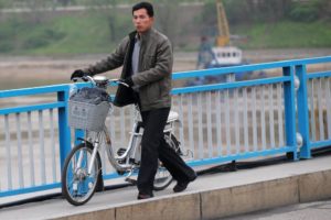 A man pushes an electric bicycle over the bridge in Pyongyang