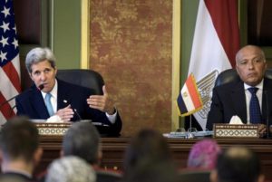 Egyptian Foreign Minister Sameh Shukri listens as U.S. Secretary of State John Kerry delivers a speech during a news conference after meetings at the Ministry of Foreign Affairs in Cairo