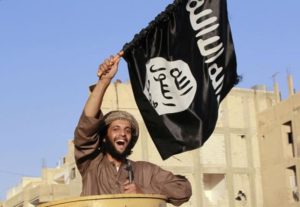 ISIS militant waving a flag, cheers as he takes part in a military parade along the streets of Syria's northern Raqqa province
