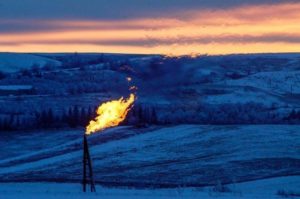 A natural gas flare on an oil well pad burns as the sun sets outside Watford City, North Dakota January 21, 2016. REUTERS/Andrew Cullen/Files