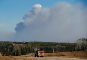 A fire truck drives down a highway in front of the Fort McMurray wildfires in Kinosis