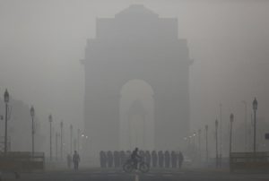A man rides his bicycle next to Indian soldiers marching in front of India Gate on a smoggy morning in New Delhi, India, December 1, 2015. REUTERS/Anindito Mukherjee