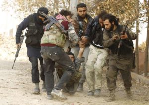 Free Syrian Army fighters carry a wounded comrade during clashes with Assad’s forces, near a crucial strategic stronghold outside Aleppo.