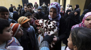 Residents queue to receive new and second-hand clothes as part of humanitarian aid at a school in Aleppo. File photo.