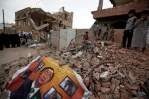 A defaced poster of the U.N. Secretary-General Ban Ki-moon is seen on the rubble of a house during a vigil marking one year since a Saudi-led air strike on a residential area in Sanaa, Yemen