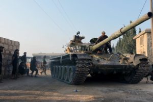 Rebel fighters ride a tank in an artillery academy of Aleppo