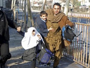 A man carries his son as they run after a blast near the Pakistani consulate in Jalalabad, Afghanistan