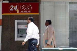 Men walk pass an automated teller machine outside Bank Al Bilad in Riyadh