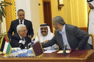 Palestinian President Abbas and Hamas leader Meshaal shake hands as Qatar's Emir Sheikh Hamad sits between them during an agreement signing ceremony in Doha