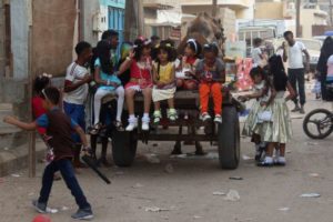 Yemeni girls sit on the back of a camel-drawn cart as people gather in the street during celebrations for Eid al-Fitr in Aden's northern Dar Saad district on July 6, 2016.PHOTO: AFP