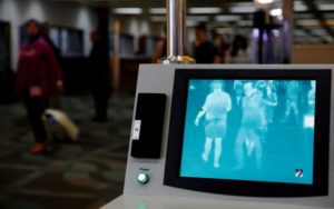 Airline passengers walk past a thermal scanner for body temperature shortly after landing from Singapore at Soekarno-Hatta airport in Jakarta