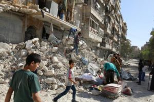 People remove belongings from a damaged site after an air strike Sunday in the rebel-held besieged al-Qaterji neighbourhood of Aleppo