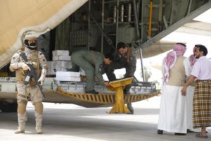 A Saudi soldier stands guard as servicemen on a Saudi military cargo plane prepare to unload aid at the international airport of Yemen's southern port city of Aden