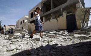 Boy walks past a house damaged by an airstrike in Yemen's capital Sanaa