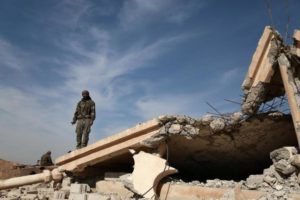 An Syrian Democratic Forces fighter stands with his weapon on the rubble of a destroyed building, north of Raqqa city