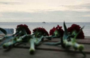 Flowers are placed on a pier as a boat of Russian Emergencies Ministry sails near the crash site of a Russian military Tu-154 plane, which crashed into the Black Sea on its way to Syria on Sunday.